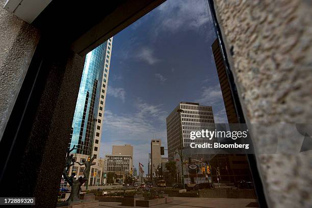 Buildings are reflected in a glass window in Winnipeg, Manitoba, Canada, on Thursday, July 4, 2013. Canada extended the longest streak of merchandise...