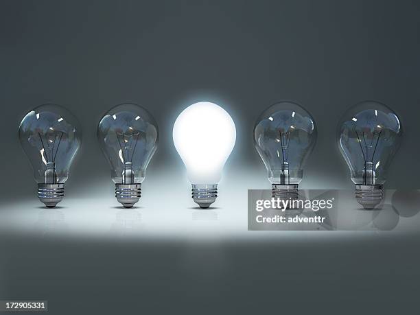 lit bulb among unlit bulbs to convey individuality - lightbulbs in a row stock pictures, royalty-free photos & images