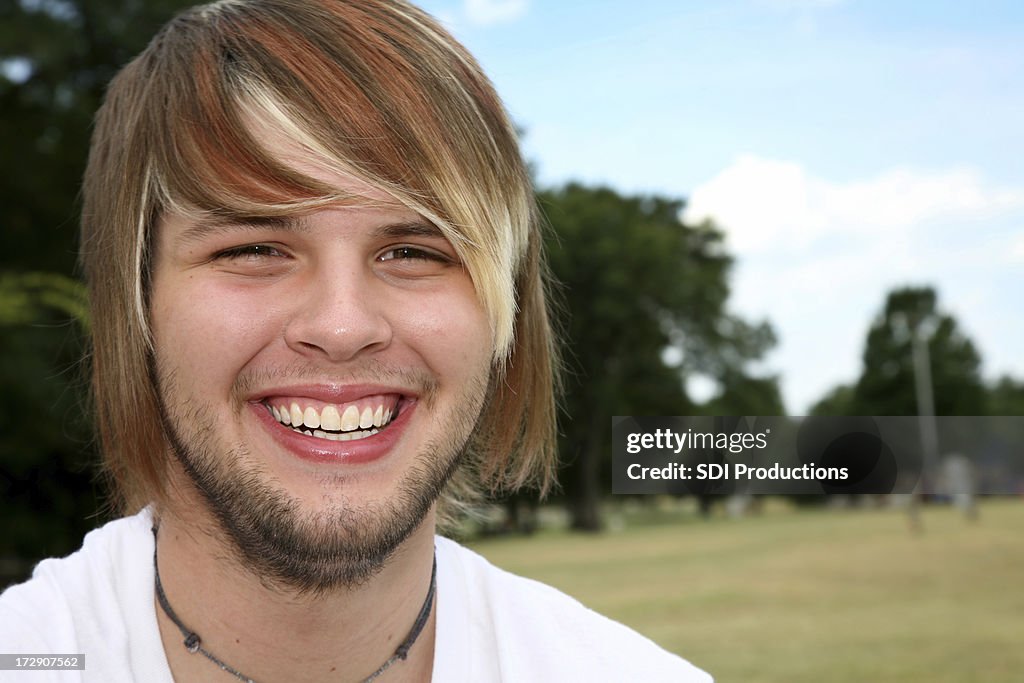 Smiling Teeange Boy With Blonde Hair Laughing At A Park