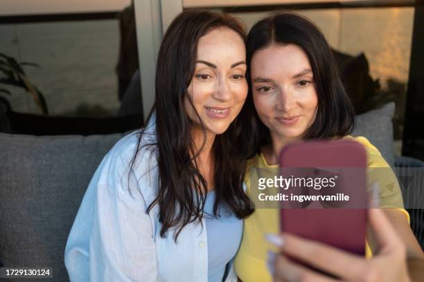 mature woman and her daughter taking selfie with mobile phone at the balcony - arab mother and daughter taking selfie imagens e fotografias de stock