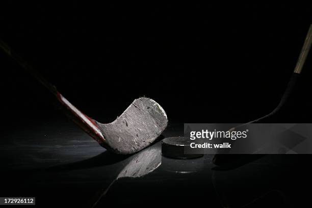 a gray hockey stick and a puck in solitude - hockeystick sportartikelen stockfoto's en -beelden