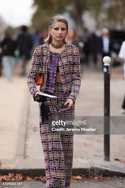 Guest is seen outside Chanel show wearing lilac star earrings, golden Chanel necklace, lilac and black colored checkered Chanel tweed jacket and...