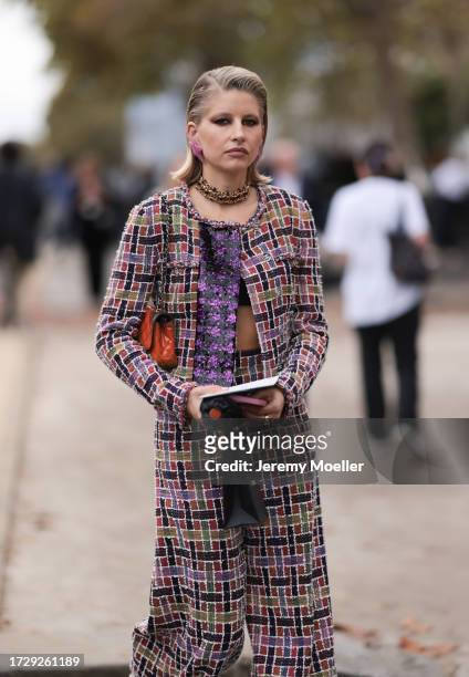 Guest is seen outside Chanel show wearing lilac star earrings, golden Chanel necklace, lilac and black colored checkered Chanel tweed jacket and...