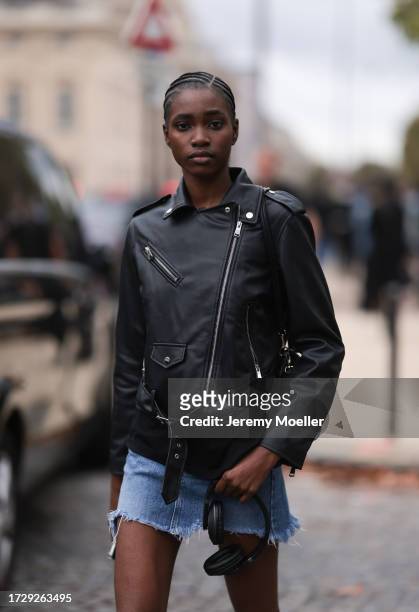 Guest is seen outside Chanel show wearing black leather jacket, denim shorts and army printed crocs during the Womenswear Spring/Summer 2024 as part...