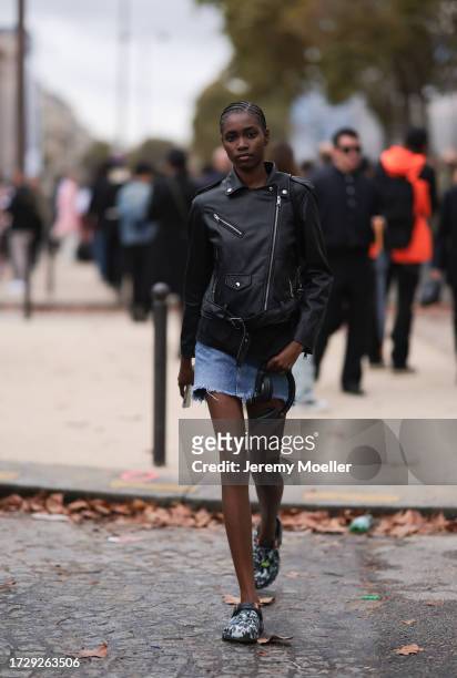 Guest is seen outside Chanel show wearing black leather jacket, denim shorts and army printed crocs during the Womenswear Spring/Summer 2024 as part...