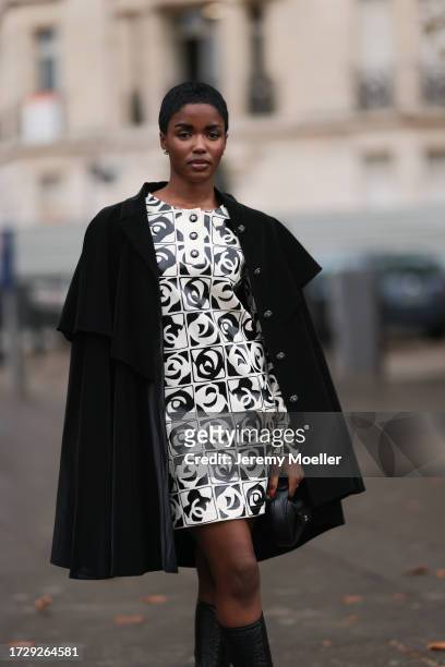 Guest is seen outside Chanel show wearing black Chanel cape, black and white Chanel logo dress, black Chanel leather handbag during the Womenswear...