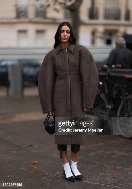 Guest is seen outside Chanel show wearing brown oversized round shaped coat, black leather handbag, white socks and black ballet flats during the...