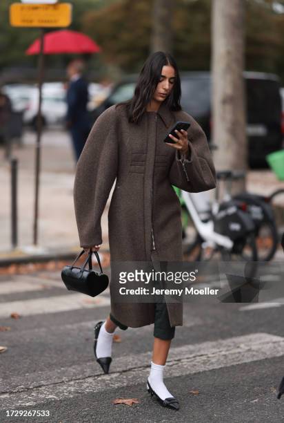 Guest is seen outside Chanel show wearing brown oversized round shaped coat, black leather handbag, white socks and black ballet flats during the...