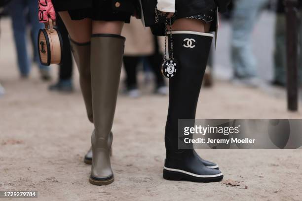 Guests are seen outside Chanel show wearing black silk Chanel headscarfs, black Chanel sunnies, silver and gold Chanel jewelry, colorful Chanel logo...
