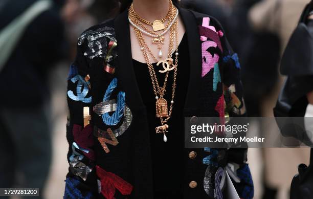 Guests are seen outside Chanel show wearing black silk Chanel headscarfs, black Chanel sunnies, silver and gold Chanel jewelry, colorful Chanel logo...