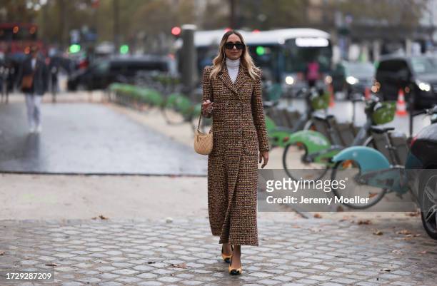 Candela Pelizzais seen outside Chanel show wearing black Chanel sunnies, white shirt underneath, beige and black checkered Chanel coat, black and...
