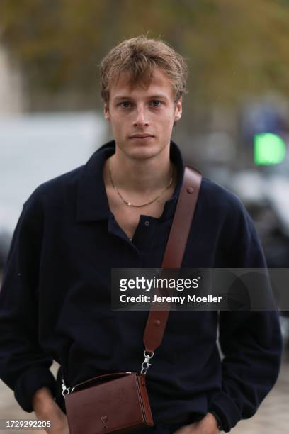 Hugh Laughton-Scott is seen outside Chanel show wearing golden necklace, navy blue sweater, brown leather Ami Paris handbag, dark blue jeans and...
