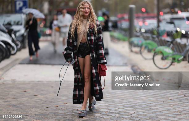 Guest is seen outside Chanel show wearing beige knitted Chanel top, black, white and red checkered Chanel coat, black short leather panties, grey...