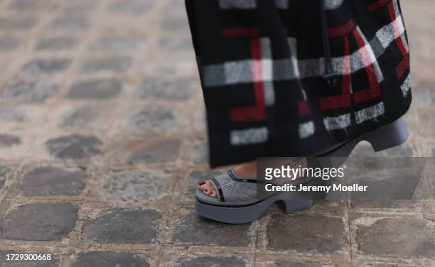 Guest is seen outside Chanel show wearing beige knitted Chanel top, black, white and red checkered Chanel coat, black short leather panties, grey...