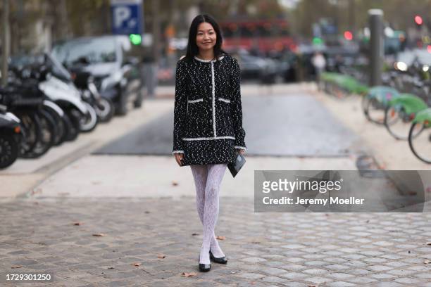 Guest is seen outside Chanel show wearing black and white tweed Chanel jacket and matching short skirt, white lace tights and black patent ballet...