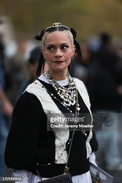 Guest is seen outside Chanel show wearing crystal Chanel hair detail, black and white Chanel sweater, Chanel pearl necklaces, black Chanel wallet on...