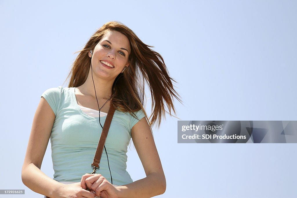 Schöne junge Frau, die Musik mit Kopfhörer Enjoyng unter blauen Himmel