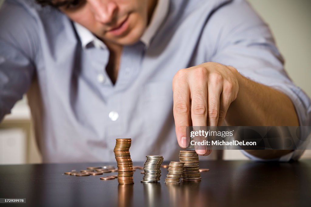 Man counting stacks of coins on table