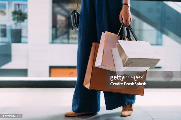 una hermosa mujer irreconocible sosteniendo sus bolsas de compras - woman holding legs fotografías e imágenes de stock