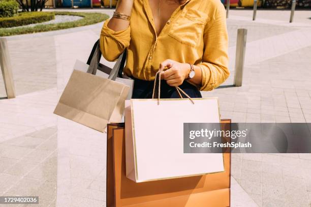 an unrecognizable beautiful woman holding her shopping bags - hand shopping bag stock pictures, royalty-free photos & images