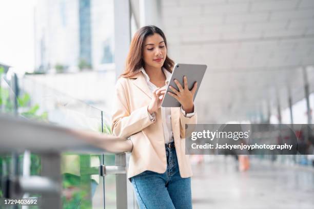 in the metropolis, an asian businesswoman works on a computer tablet. - vragenlijst stockfoto's en -beelden