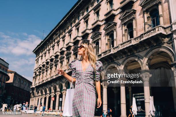 beautiful businesswoman with sunglasses looking away while walking on the street - milan fashion stock pictures, royalty-free photos & images