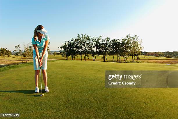 woman on golf field ready to put ball - women's golf stockfoto's en -beelden