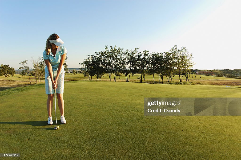 Woman on golf field ready to put ball