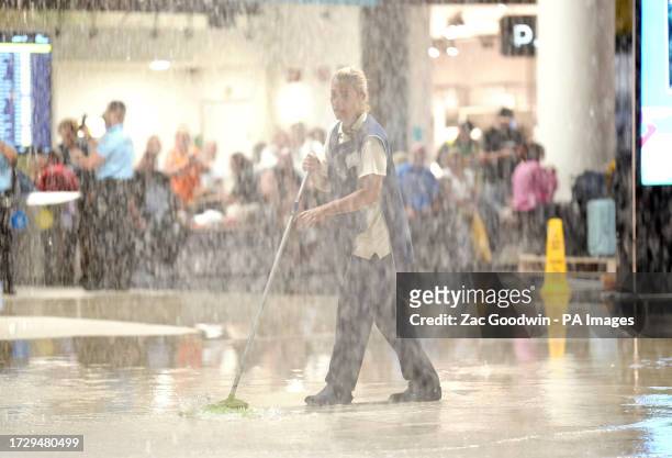 Staff sweep away water from inside Faro airport in Portugal after heavy rain caused flooding. Issue date: Tuesday October 17, 2023.