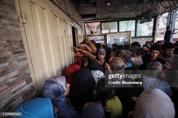 Palestinians crowd around the restricted entrance to a store to pick up limited food supplies in Khan Younis, Gaza, on Monday, Oct. 16, 2023....