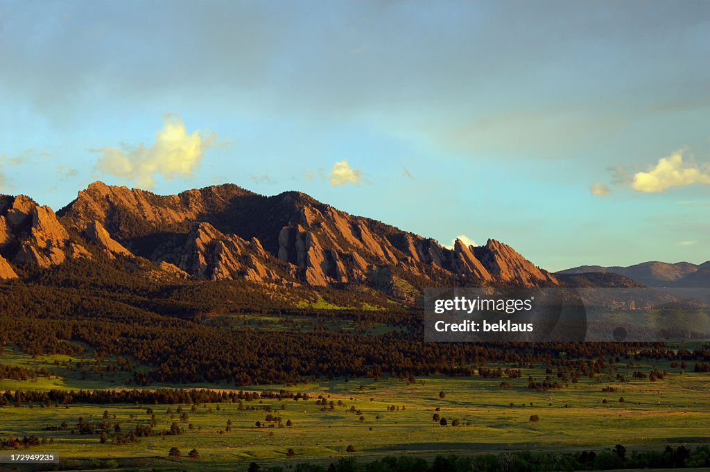 Landscape image of boulder flatirons and a lush field