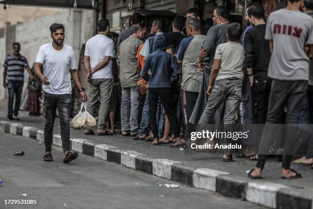 Palestinians wait in line to shop after Israeli authorities have ceased supplying electricity, water and food as Israeli airstrikes continue in Gaza...