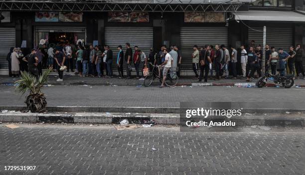 Palestinians wait in line to shop after Israeli authorities have ceased supplying electricity, water and food as Israeli airstrikes continue in Gaza...