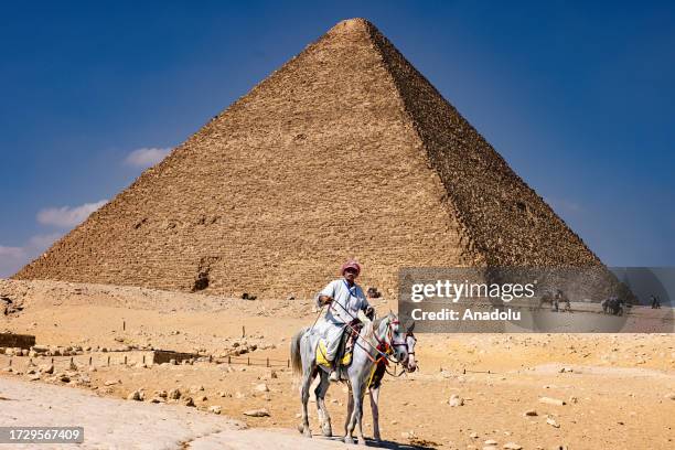 Man rides on a horse as he visits the Pyramids of Giza, including the Pyramid of Cheops, one of the Seven Wonders of the World, built by the Egyptian...