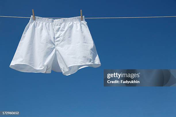 white boxer shorts clipped to clothesline against blue sky - shorts stock pictures, royalty-free photos & images
