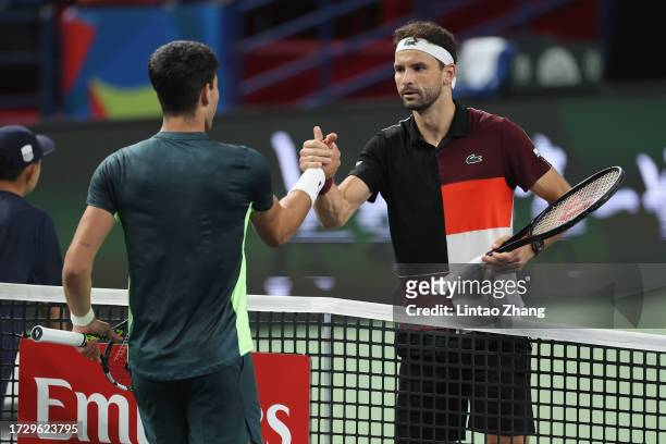 Grigor Dimitrov of Bulgaria shakes hands with Carlos Alcaraz of Spain after win the Men's Singles Round of 16 match against on Day 10 of the 2023...