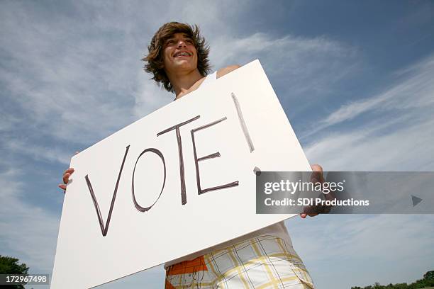 young male outside holding large sign that says vote - voter stockfoto's en -beelden