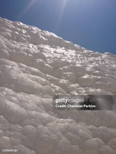 bright sunshine shining on limestone cliffs next to travertines of pamukkale thermal springs in denizli province in turkey in july 2023. site of ancient city of hierapolos. unesco world heritage site with mineral waters and shimmering rock in july 2023 - calcite stock pictures, royalty-free photos & images