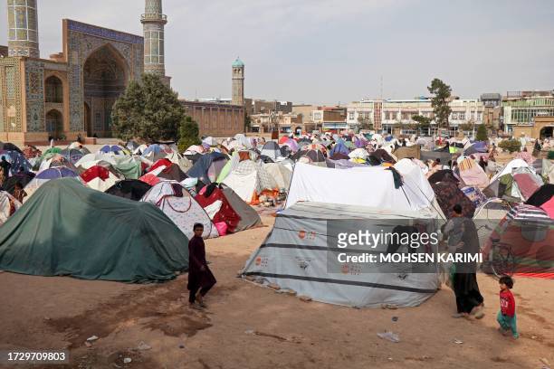 People walk past their makeshift shelters set-up after earthquake in front of the Jami Mosque in Herat on October 17, 2023. A magnitude 6.3...