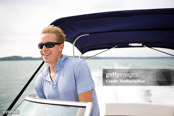 young man boating - boat steering wheel stock pictures, royalty-free photos & images