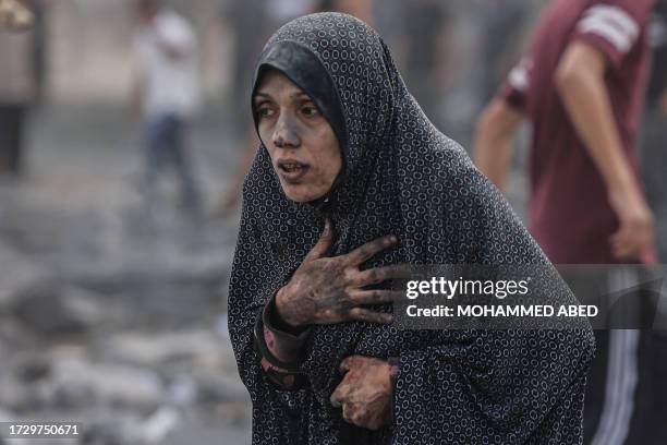 Graphic content / A Palestinian woman covered in dust, reacts following an Israeli airstrike on buildings in Rafah, in the southern Gaza Strip on...