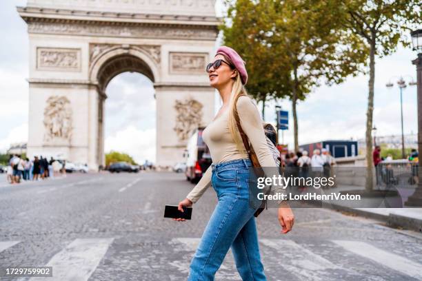 femme marchant devant l’arc de triomphe à paris - quartier des champs élysées photos et images de collection