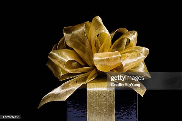 christmas gift wrapped in gold ribbons, bows on black background - gold gift boxes stock pictures, royalty-free photos & images