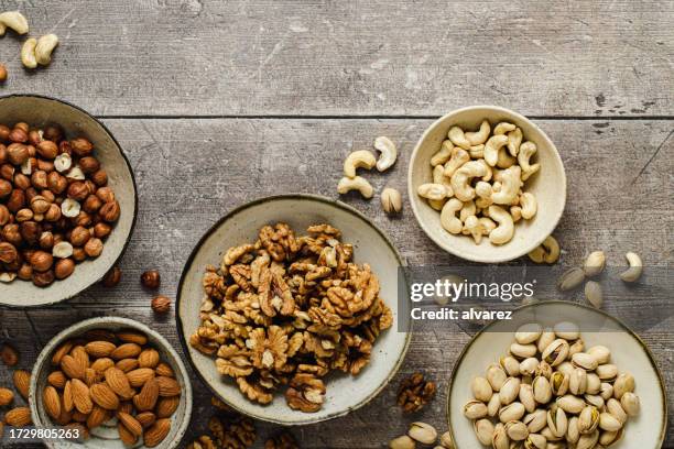 assortimento di frutta secca in ciotole su superficie di legno - dried fruit foto e immagini stock