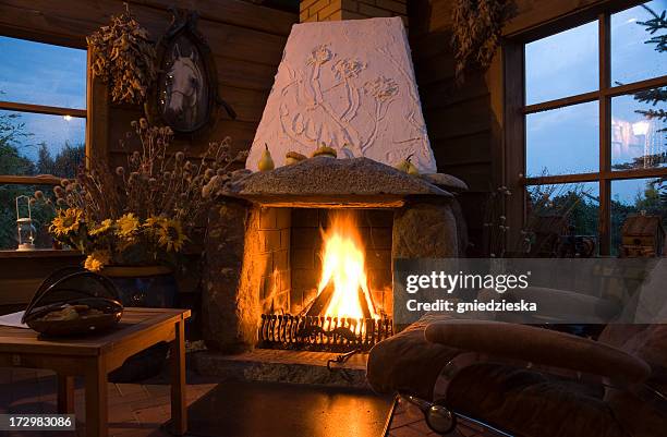 evening in a cozy living room with a large fireplace - autumn indoors stock pictures, royalty-free photos & images