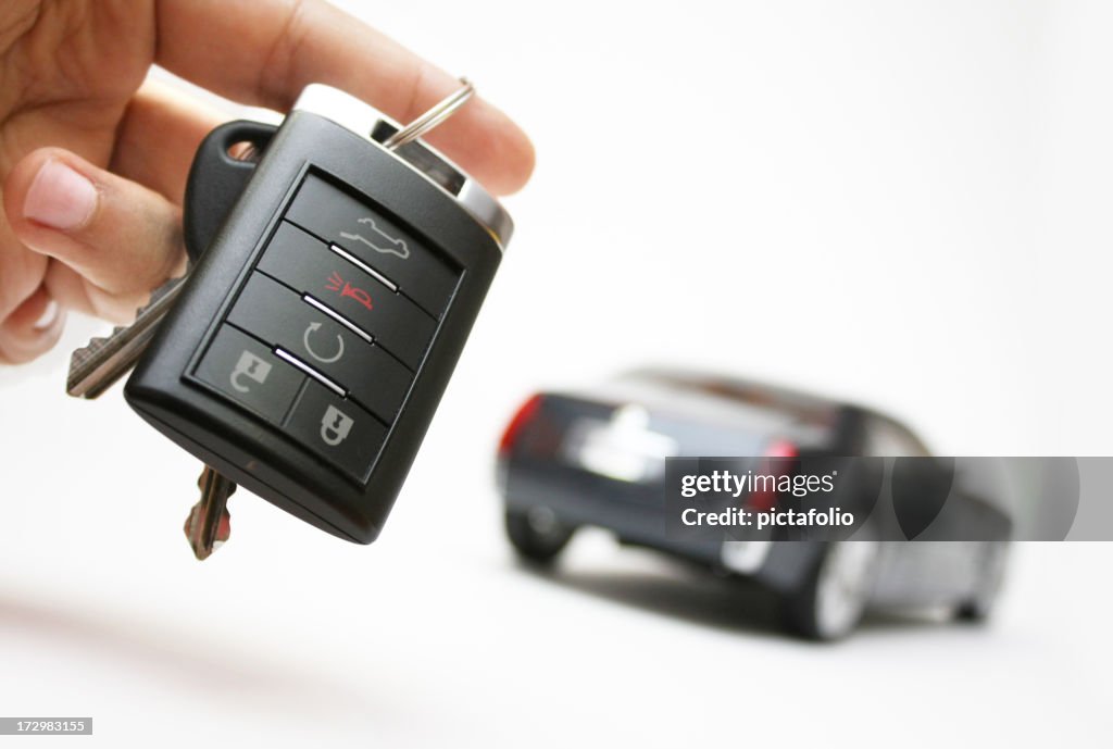 Car keys in a hand with an unfocused car in the background