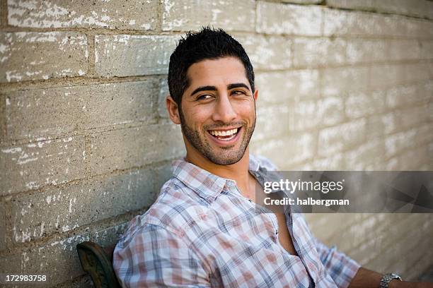 smiling young man sitting outside - high contrast stock pictures, royalty-free photos & images