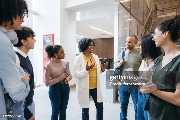 teacher talks to students in university lobby - teacher stock pictures, royalty-free photos & images