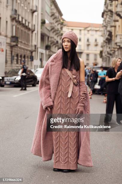 Yoyo Cao wears a pink hat, a matching pink long dress with a cross-body trail, and a pink teddy long coat outside MaxMara during the Milan Fashion...