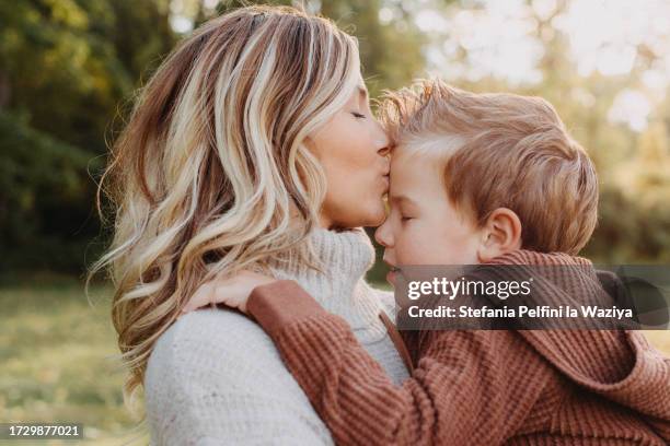 mother kissing her little boy on his forehead - forehead stock pictures, royalty-free photos & images